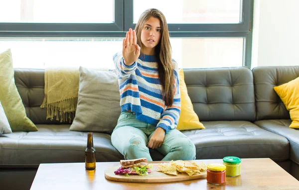 pretty woman looking serious, stern, displeased and angry showing open palm making stop gesture