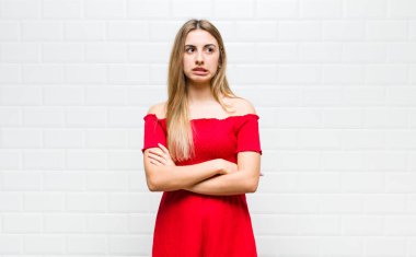 Sarışın kadın kuşkulanıyor ya da düşünüyor, dudağını ısırıyor ve kendini güvensiz ve gergin hissediyor.