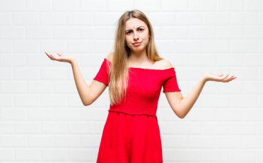 Şaşkın, şaşkın ve stresli görünen sarışın kadın, farklı seçenekler arasında merak ediyor, kararsız hissediyor.