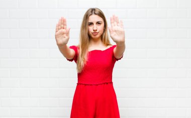 Sarışın kadın ciddi görünüyor, mutsuz, kızgın ve hoşnutsuz giriş yasaklandı ya da iki avucunun içinde de dur diyor.