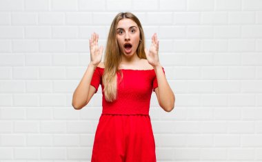 Şaşırmış ve şaşkın bakan sarışın bir kadın, inanılmaz bir şey fark ettiğinde çenesi şaşkın ve şaşkın
