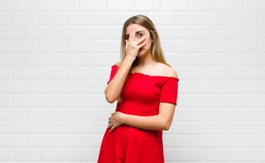 Sarışın kadın korkmuş ya da utanmış hissediyor. Gözleri yarı kapalı ya da ellerle dikizliyor ya da dikizliyor.