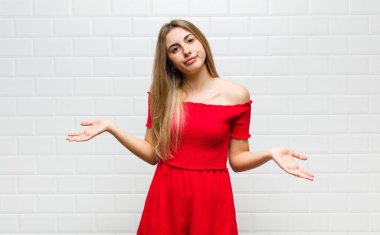 Sarışın kadın şaşkın ve şaşkın hissediyor, doğru cevap ya da karardan emin değil, bir seçim yapmaya çalışıyor.