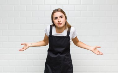blonde woman feeling clueless and confused, having no idea, absolutely puzzled with a dumb or foolish look