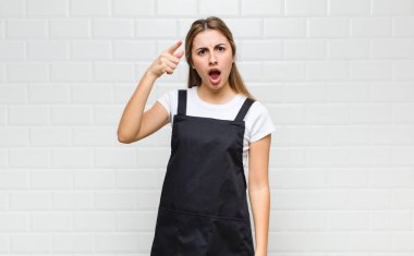 Kızgın agresif bir ifadeyle kameraya bakan sarışın bir kadın kızgın, çılgın bir patron gibi görünüyor.