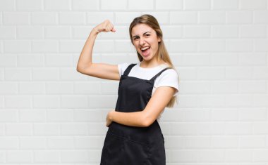 Sarışın kadın kendini mutlu, tatmin olmuş ve güçlü hissediyor, kaslı ve formda, spor salonundan sonra güçlü görünüyor.