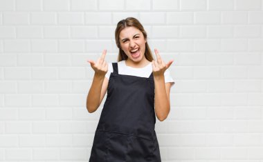 Sarışın kadın kışkırtıcı, agresif ve müstehcen hissediyor. İsyankar bir tavırla orta parmağını hareket ettiriyor.