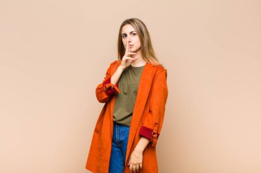 Sarışın kadın sessizlik ve sessizlik istiyor, parmağıyla ağzının önünde işaret ediyor, 