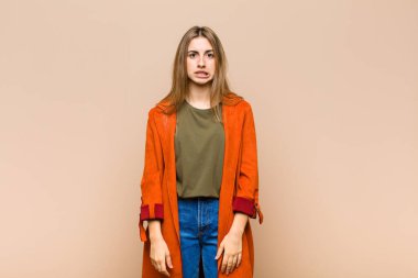 Sarışın kadın şaşkın ve şaşkın görünüyor. Sinirli bir hareketle dudağını ısırıyor. Sorunun cevabını bilmiyor.