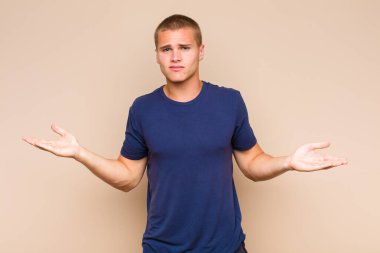 Şaşkın, şaşkın ve stresli görünen sarışın bir adam. Farklı seçenekler arasında merak ediyor. Belirsiz hissediyor.