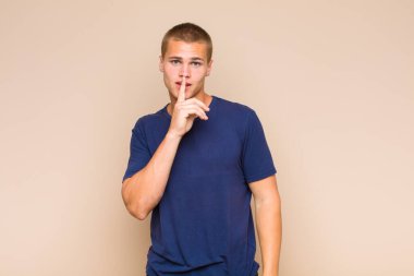 Sarışın adam ciddi görünüyor ve parmaklarını dudaklarına bastırıp sessizlik ya da sessizlik talep ediyor, sır saklıyor.