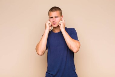 Sarışın adam sinirli, stresli ve sinirli görünüyor, iki kulağını da sağır edici bir ses, ses ya da yüksek sesle kapatıyor.