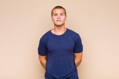 Sarışın adam pozitif ve kendinden emin gülümsüyor. Tatmin olmuş, arkadaş canlısı ve mutlu görünüyor.