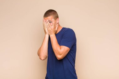 Sarışın adam korkmuş ya da utanmış hissediyor. Gözleri yarı kapalı ya da elleri açık bir şekilde dikizliyor.