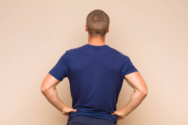 Sarışın bir adam kafası karışık mı yoksa şüphe ve soru dolu mu? Elleri kalçasında, dikiz aynasından merak ediyor.