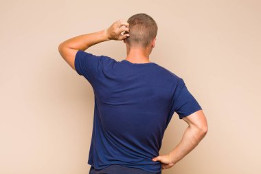 Sarışın adam bilgisiz ve kafası karışık, bir çözüm düşünüyor, eli kalçasında, diğeri kafasında, dikiz aynasından.