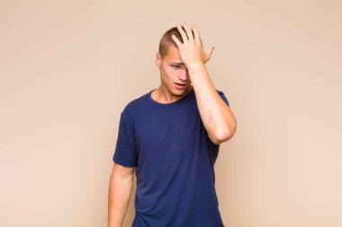 blonde  man raising palm to forehead thinking oops, after making a stupid mistake or remembering, feeling dumb