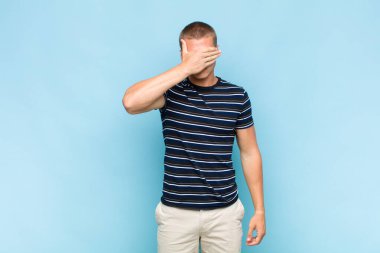 Sarışın adam tek eliyle gözlerini kapatıyor. Korkmuş ya da endişeli, merak ediyor ya da körü körüne bir sürpriz bekliyor.