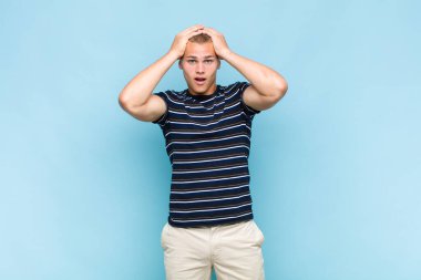 Sarışın adam heyecanlı ve şaşırmış görünüyor, ağzı açık, elleri başının üstünde, şanslı bir kazanan gibi hissediyor.