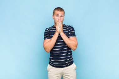 Sarışın adam endişeli, üzgün ve korkmuş hissediyor, elleriyle ağzını kapatıyor, endişeli ve berbat görünüyor.