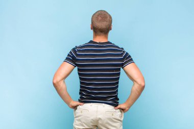 Sarışın bir adam kafası karışık mı yoksa şüphe ve soru dolu mu? Elleri kalçasında, dikiz aynasından merak ediyor.