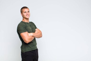 Sarışın adam kameraya çapraz kollarıyla gülümsüyor ve mutlu, kendinden emin, tatmin olmuş bir yüz ifadesi var.