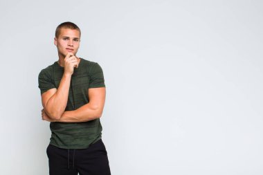 Sarışın adam mutlu görünüyor ve gülümsüyor, çenesi açık, merak ediyor ya da soru soruyor, seçenekleri karşılaştırıyor.