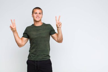 Sarışın adam gülümsüyor ve mutlu görünüyor, arkadaş canlısı ve tatmin olmuş, zafer ya da barış işareti yapıyor.