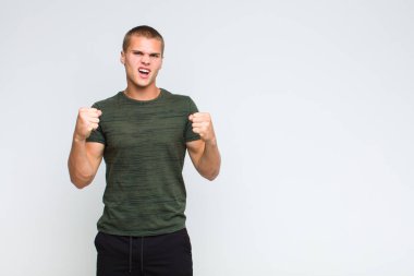 Sarışın adam sinirli, sinirli, sinirli bakışlı ve yumruklarını sıkmış, öfkeli bir şekilde bağırıyor.