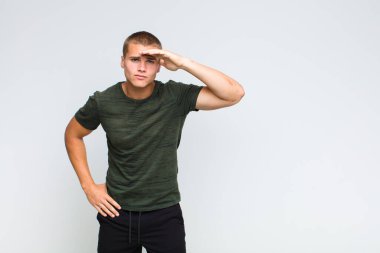 Sarışın adam şaşkınlık ve şaşkınlık içinde bakıyor. Alnı açık, uzaklara bakıyor, izliyor ya da arıyor.