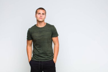 Sarışın adam gururlu, kendinden emin, havalı, küstah ve kibirli görünüyor, gülümsüyor, başarılı hissediyor.