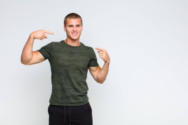 Sarışın adam kendinden emin bir şekilde gülümseyerek kendi geniş gülüşünü, pozitif, rahat, tatmin olmuş tavrını gösteriyor.