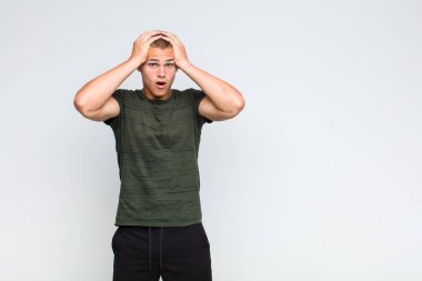 Sarışın adam heyecanlı ve şaşırmış görünüyor, ağzı açık, elleri başının üstünde, şanslı bir kazanan gibi hissediyor.