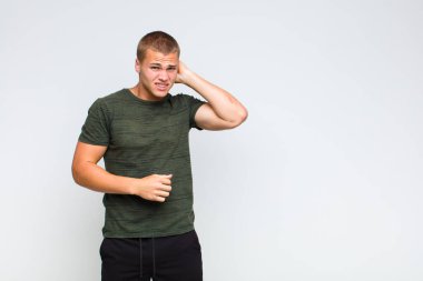 Sarışın bir adam stresli, hayal kırıklığına uğramış ve yorgun, endişeli ve sorunlu bir bakışla boynunu okşuyor.