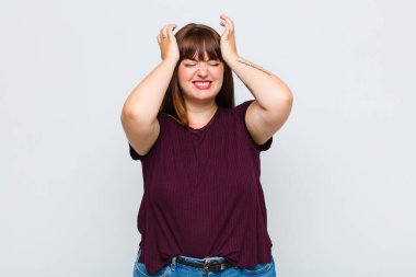 Aşırı kilolu kadın stresli ve endişeli, depresyonda ve baş ağrısı yüzünden hayal kırıklığına uğramış, iki elini de başa kaldırıyor.