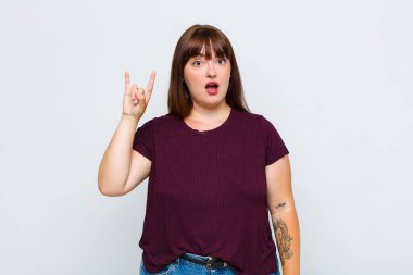 Kilolu bir kadın kendini mutlu, eğlenceli, kendinden emin, pozitif ve asi hissediyor, elle kaya ya da heavy metal işareti yapıyor.