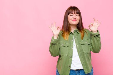 Kilolu kadın konsantre olmuş ve meditasyon yapıyor gibi görünüyor, tatmin olmuş ve rahatlamış hissediyor, düşünüyor ya da bir seçim yapıyor.
