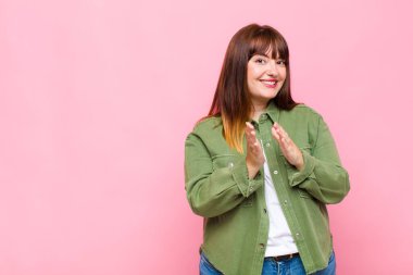 Kilolu kadın mutlu ve başarılı hissediyor, gülümsüyor ve alkışlıyor, alkışlarla tebrik ediyor.