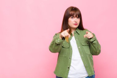 Şişman kadın kameraya hem parmaklarını hem de kızgın yüzünü göstererek sana görevini yapmanı söylüyor.