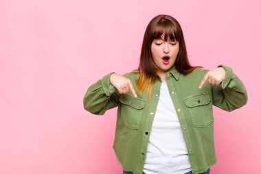 Şişman kadın şok olmuş, ağzı açık ve şaşkın, inançsızlık ve şaşkınlık içinde bakıyor ve onu işaret ediyor.