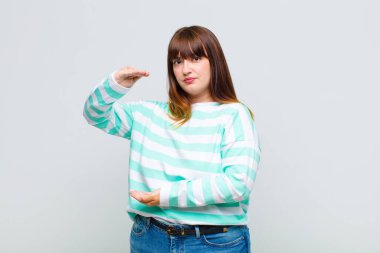 İki eli de kenarda olan bir objeyi tutan kilolu bir kadın fotokopi alanında bir nesneyi gösteriyor, sunuyor ya da reklamını yapıyor.