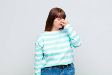 Kilolu bir kadın stresli, mutsuz ve hayal kırıklığına uğramış, alnına dokunmuş ve şiddetli baş ağrısı çeken bir kadın.