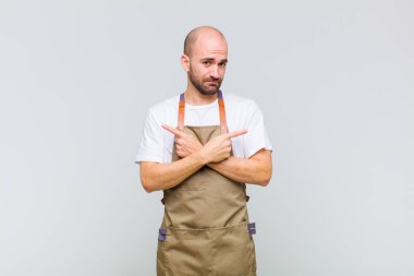 Kafası karışmış, kafası karışmış, güvensiz ve şüpheyle zıt yönlere bakan kel bir adam.