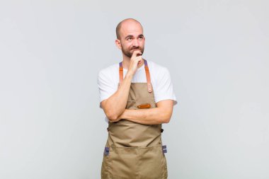 Kel düşünen, kuşkulu ve kafası karışık, farklı seçenekleri olan, hangi kararı vereceğini merak eden bir adam.