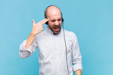 Kel adam mutsuz ve stresli görünüyor, intihar jesti elle silah işareti yapıyor, kafasını işaret ediyor.