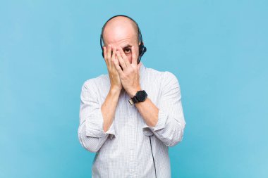 Kel bir adam korkmuş ya da utanmış hisseder. Gözleri yarı kapalı bir şekilde dikizler ya da gözetler.