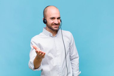 Kel adam gülümsüyor, mutlu görünüyor, kendinden emin ve arkadaş canlısı, anlaşma yapmak için el sıkışmayı teklif ediyor, işbirliği yapıyor.