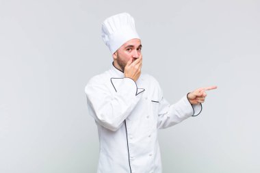 Kel adam kendini mutlu, şaşkın ve şaşırmış hissediyor. Ağzını eliyle kapatıyor ve yanal kopya alanını işaret ediyor.