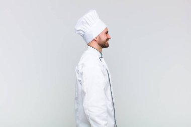 Kel adam profil görünümünde. İlerideki boşluğu kopyalamak istiyor. Düşünüyor, hayal ediyor ya da hayal ediyor.