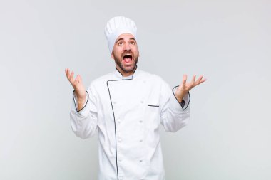 Kel adam kendini mutlu, şaşkın, şanslı ve şaşırmış hissediyor. Zaferi kutlarken iki eli havada.